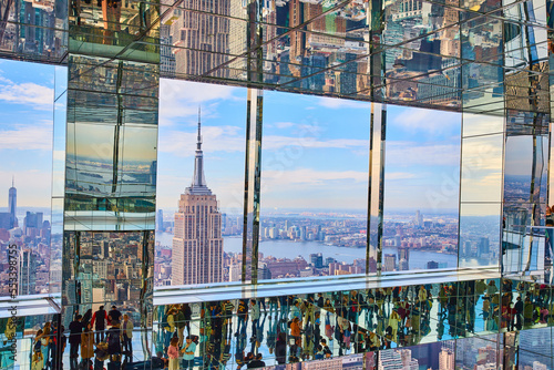 Stunning Empire State Building viewed high up in reflective mirror skyscraper with tourists