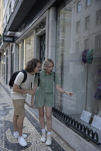 Surprised tourist couple window shopping. Woman pointing at product. Travelling, tourism, romance concept