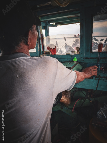 boat driver in wheelhouse, east kalimantan, indonesia, december 13, 2022