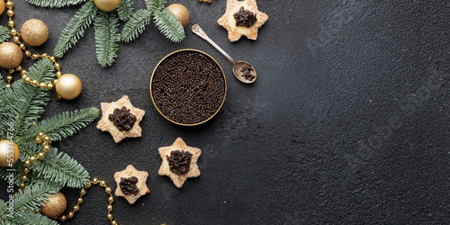 Black caviar appetizers stars on a christmas decorated black table Horizontal banner with copyspace