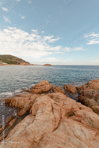 Panorámica del mar Mediterráneo desde el famoso castillo de Tossa del Mar con las rocas en primer plano y la verde montaña al fondo.