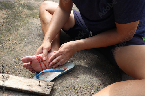 An Asian man shows a foot wound after stepping on a rusty nail on a wood. The wound from the foot was bleeding profusely. It's very painful and can damage nerves. It's time for a tetanus shot.