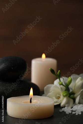Beautiful composition with spa stones, burning candles and flowers on black table