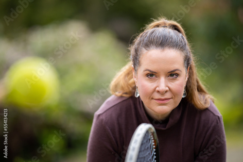 female tennis player practicing forehands and hitting tennis balls on a grass court in england