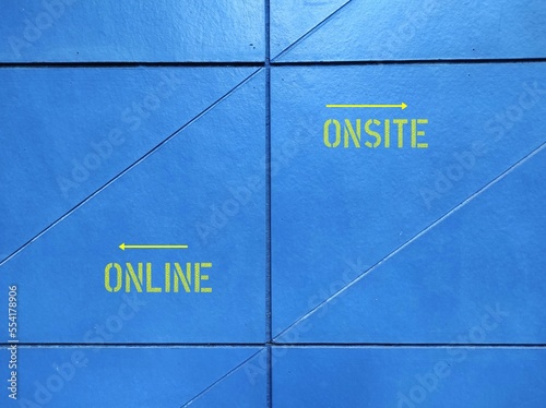 Blue wall with text and direction to ONLINE and ONSITE, concept of education and work in pandemic lockdown, digital revolution turns conventional working - or hybrid combination