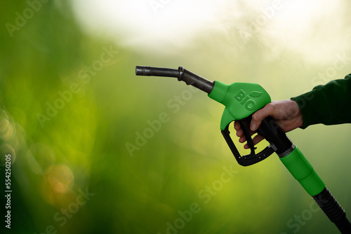 Hand with fuel nozzle with inscription BIO. Carbon neutral bio fuel decarbonization concept