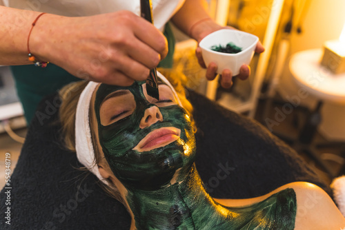 Close up of a face of a woman with black mud skin mask at a spa beauty salon. High quality photo