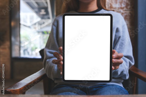 Mockup image of a woman holding and showing digital tablet with blank white desktop screen