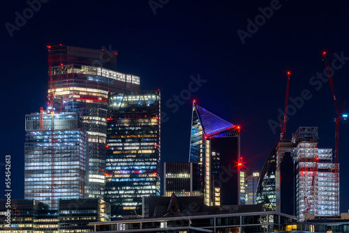 Contemporary building walkie talkie in the heart of the City of London and tower cluster lightening in the night, handheld shot.