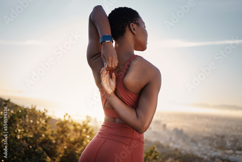 Fitness, black woman and stretching arm on mountain in Cape Town for muscle wellness, healthy goals and energy. Athlete, warm up and mobility for workout, sports exercise and start training in nature