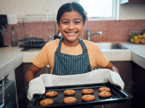 Girl kid, cookies and baking with portrait and bakery skill, learning and development with success and pride. Cookie, dessert and proud child baker cooking in kitchen with achievement and happiness.