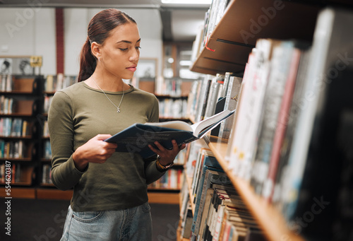 Black woman reading book in a library for education, studying and research in school, university or college campus. Focus, book and student at bookshelf for language learning or philosophy knowledge