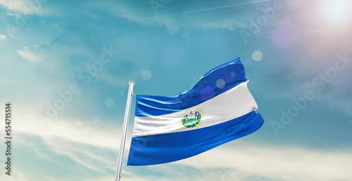 waving flag of El Salvador in blue sky. the symbol of the state on wavy cotton fabric.