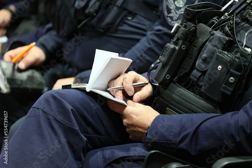 Policjant z notatnikiem służbowym na odprawie do służby. 