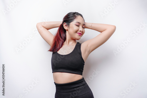 Smiling sporty Asian woman wearing sportswear is relaxing after working out