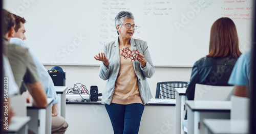 Education, university professor and students in classroom for lecture on innovation in science, physics or math. Focus, attention and woman college teacher in presentation with diversity in learning.