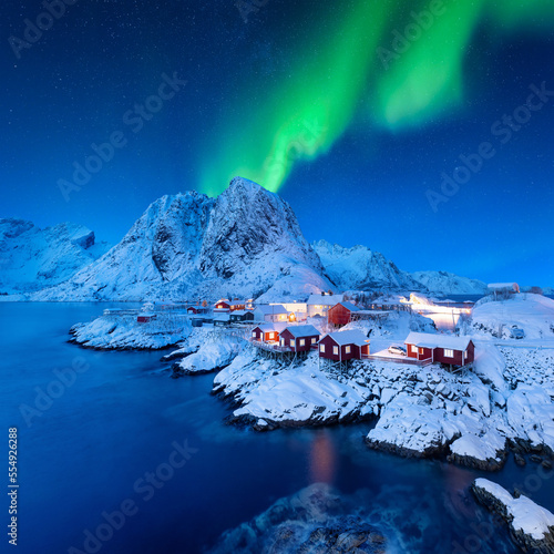Aurora Borealis. Northern Lights. View on the house in the Hamnoy village, Lofoten Islands, Norway. Landscape in winter time. Mountains and water.