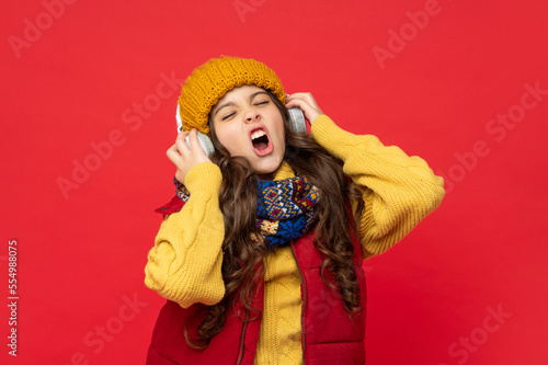 shouting teen girl in hat and earphones. modern life in childhood. child listen music in headphones
