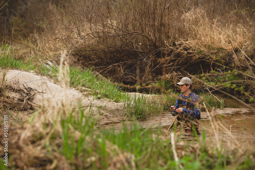young man kneeling in trout stream