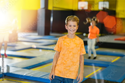 Portrait of smiling preteen boy spending time in modern inflatable amusement park, posing in trampoline arena..