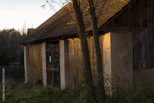 Stara stodoła murowana i z drewna , o dachu pokrytym betonowymi ( cementowymi ) dachówkami . Jesień - zachód słońca .