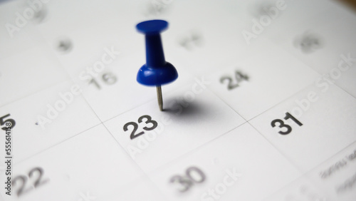 Embroidered blue pins on a calendar on the 23 th with selective focus