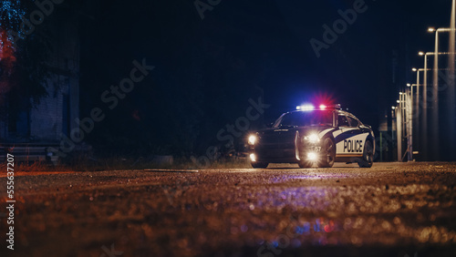 Low Angle Shot of a Stopped Police Car with Lights and Siren on During a Misty Night. Patrolling Vehicle on Stand by, Waiting for Orders to Start Pursuing Suspects. Police Enforcement