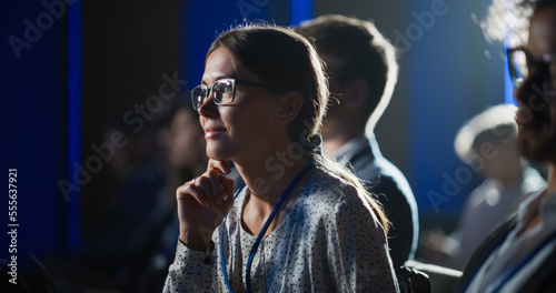 Close up Portrait of Young Enthusiastic Female Attending a Motivational Speaker Event, Sitting in a Crowded Concert Hall, Leaning Closer to the Stage and Listening Carefully to the Presentation.