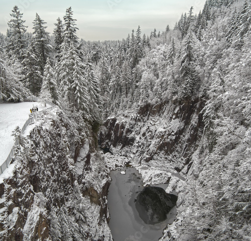 Looking down into the abyss of the Cleveland Dam and frozen Capilano River surrounded by the snowy winter landscape at the Capilano Lake Regional Park in North Vancouver, British Columbia, Canada