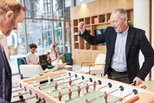 Businessman cheering while playing football at the foosball table