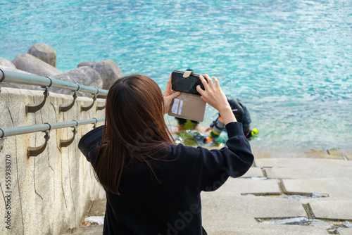 スマートフォンで海を撮影する女性
