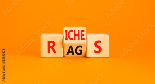 Rags or riches symbol. Concept word Rags Riches on wooden cubes. Beautiful orange table orange background. Business and rags or riches concept. Copy space.