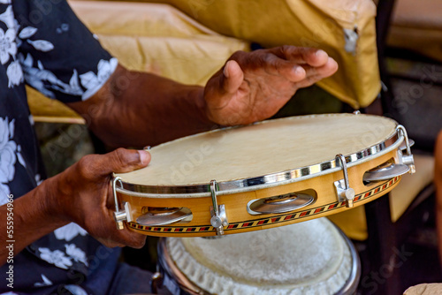 Hands and instrument of musician playing tambourine in the streets of Salvador in Bahia during a samba performance during carnival