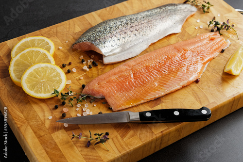 Fresh trout fillets with skin on a wooden cutting board, prepared for frying.