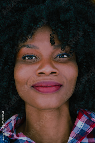 Portrait of a young Latina, haitian and African-American woman with curly hair looking at the camera. Vertical photo.