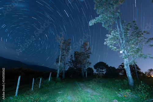Star trails. Movement of stars in the sky towards the south pole. Country road in the mountain at night.