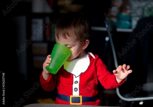 Portrait of cute little boy in Santa clothes drinking water