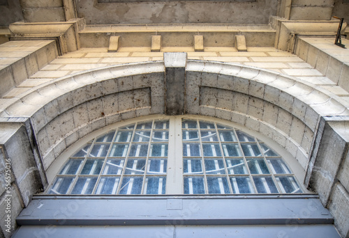 Entrance detail on late 19th century limestone building showing stone archway and keystone above an arched paned window