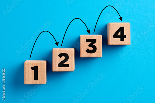 Step by step progress in business planning, career improvement or problem solving concept. Numbers with arrows on wooden cubes.