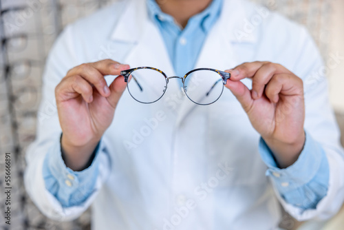 Man in a lab coat holding eyeglasses in hands