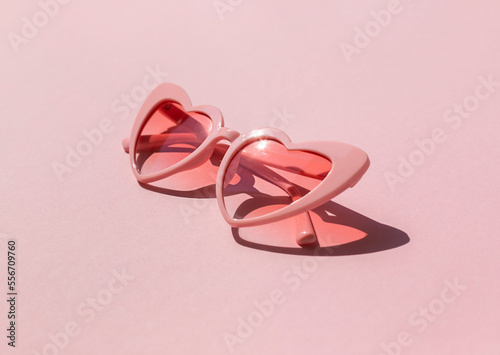 Heart shaped sunglasses on the pink background. Valentine's day concept composition 