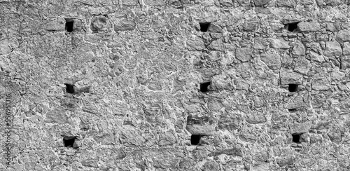 gray monochrone texture of an anciant old castle wall with little windows embrasures