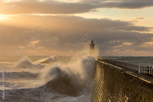 Big waves batter the lighthouse & north pier guarding the mouth of the Tyne in Tynemouth at sunrise, England 