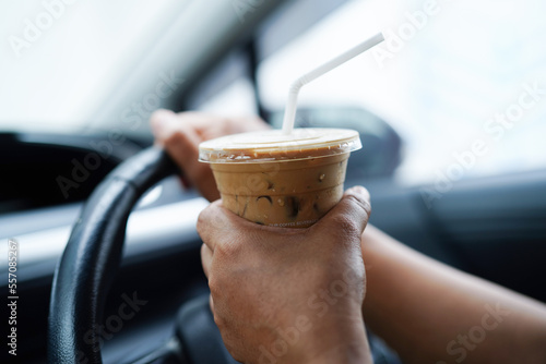 Asian woman driver hold ice coffee cup and sandwich bread for eat and drink in car, dangerous and risk an accident.