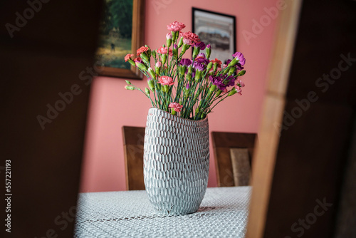 wazon z różowymi goździkami na stole