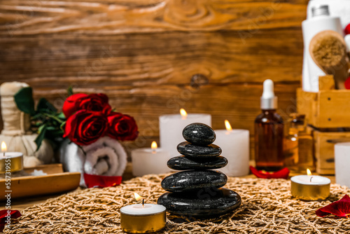 Spa stones with burning candle on wooden table, closeup. Valentine's Day celebration