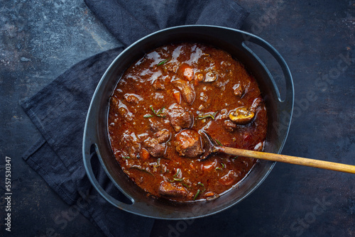 Traditionelles ungarisches geschmortes Hirschgulasch mit Gemüse und Kräutern in würziger Sauce serviert in einem Design Schmortopf