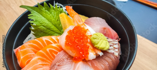 Raw fish in Japanese style, Sashimi, in black bowl, tuna, salmon, snapper, egg, served with wasabi