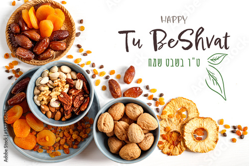 Mix of dry fruits and nuts in a wicker plate, branch with young green leaves. Concept of the Jewish holiday. Vertical banner with the inscription Tu Bishvat in English and Hebrew