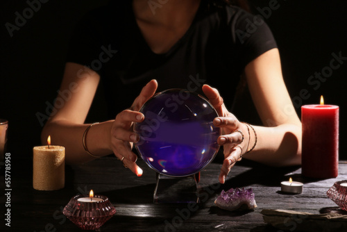 Soothsayer using crystal ball to predict future at table in darkness, closeup